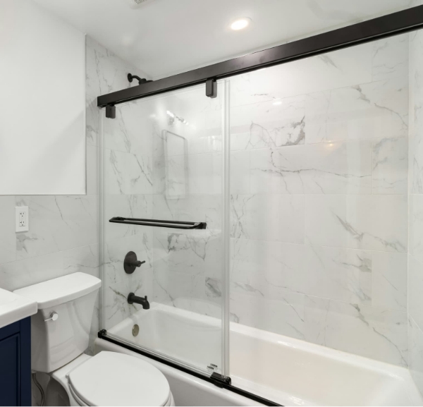 Elegant bathroom with a marble countertop, wall tile and glass shower door, showcasing bathtub remodeling services in Destin