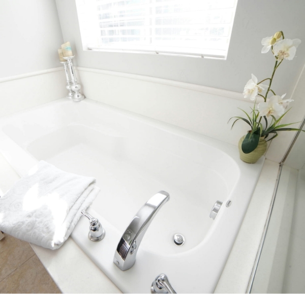 A pristine white bathtub featuring a vase of flowers, representing a tranquil space for bath remodeling services in Fort Walton Beach