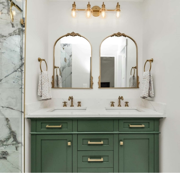 A green bathroom featuring gold fixtures and elegant marble countertops, showcasing a luxurious upgrade in Fort Walton Beach.
