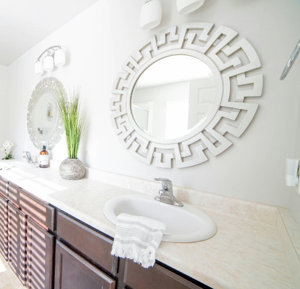 A bathroom interior with a prominent large mirror and a sleek sink, creating an open and airy atmosphere.