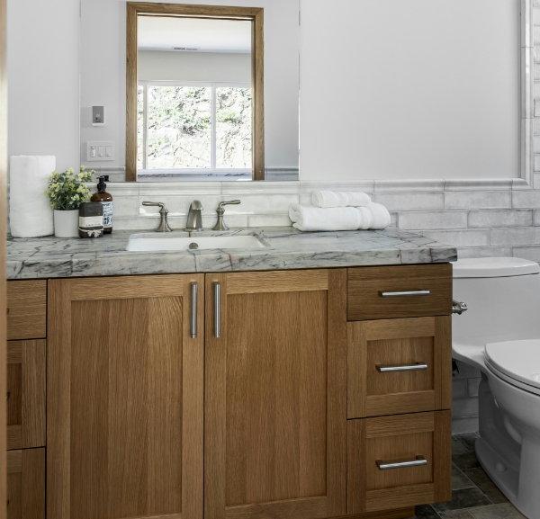 A well-appointed bathroom with a toilet, sink, mirror, and a stylish dark wood vanity enhancing the space.