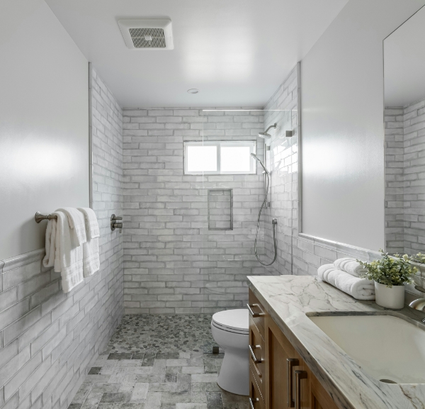 A modern bathroom featuring white tiled walls, a sink, and a spacious walk-in shower.