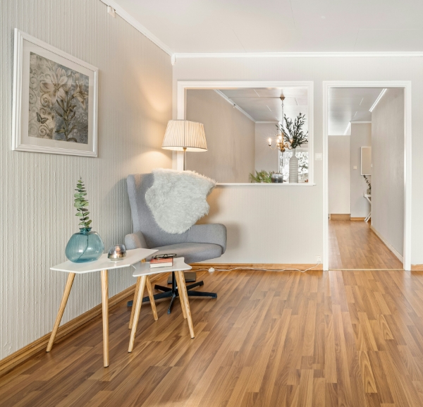 A room featuring a wooden floor and a single chair positioned in the center.